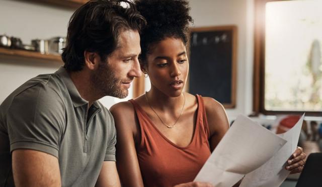 Couple looking at paper and computer