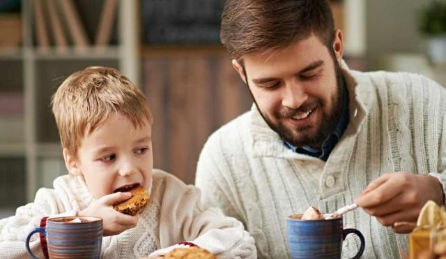 Father and son drinking hot chocolate at the kitchen table.