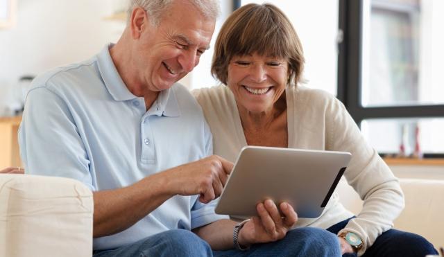 Older couple smiling at their tablet.