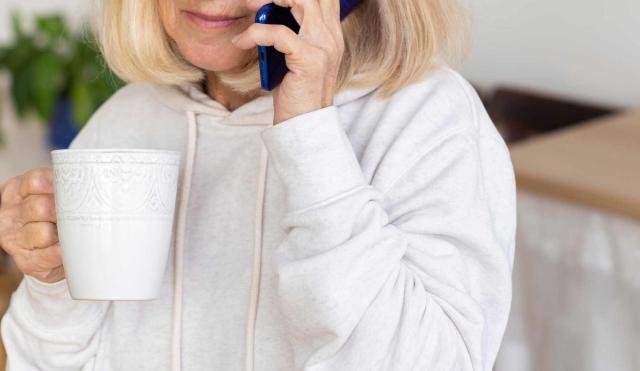 woman holding phone and cup of coffee