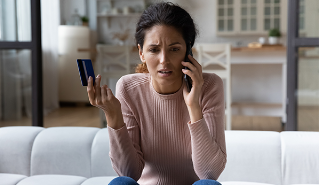confused woman on phone holding a credit card