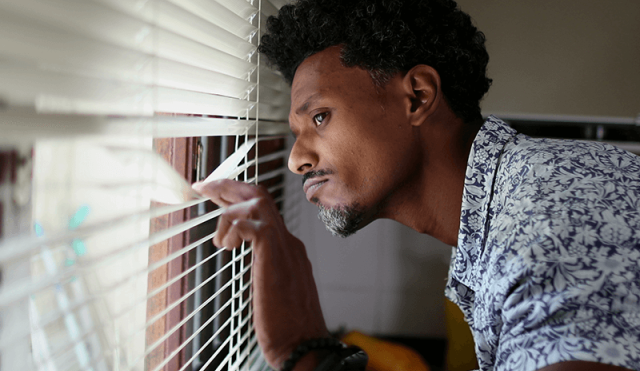 Suspicious man looking out window