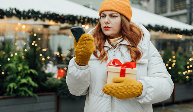 Woman holding a gift looking confused at her phone