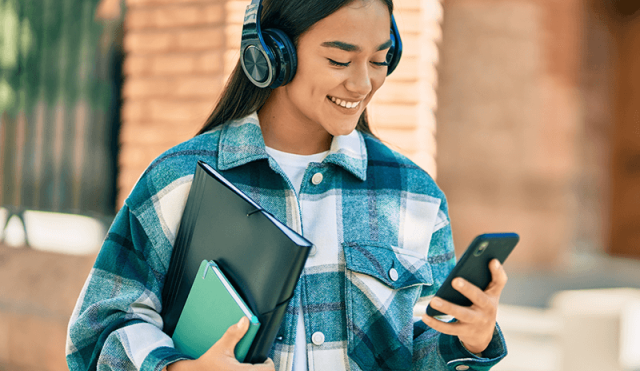 student with headphones looking at phone