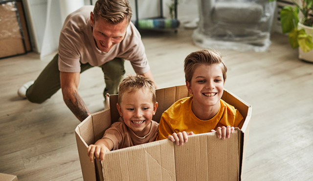 Father pushing two children in a box