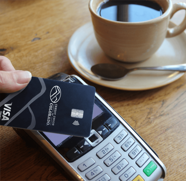 Hand holding a credit card using Tap to Pay for coffee