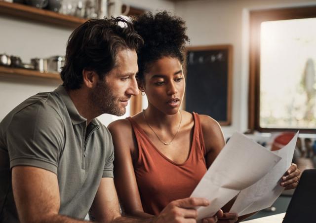 Couple looking at paper and computer