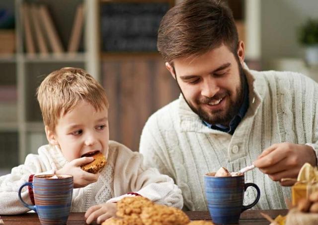 Father and son drinking hot chocolate at the kitchen table.