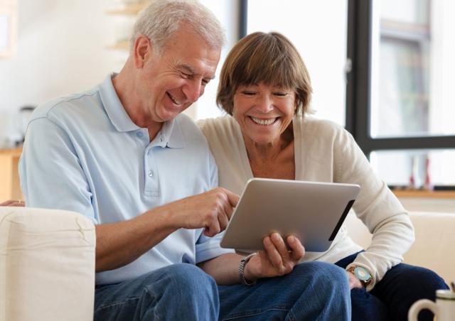 Older couple smiling at their tablet.