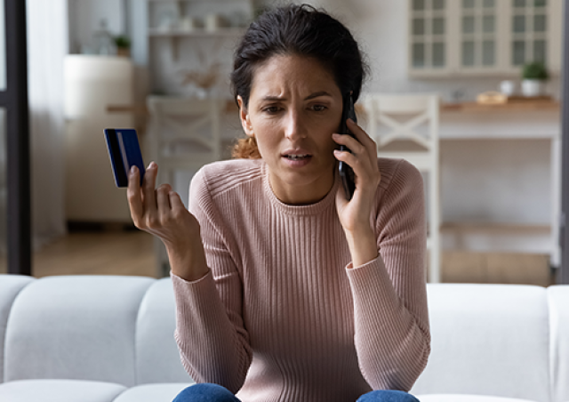 confused woman on phone holding a credit card