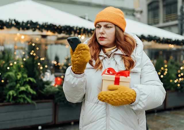 Woman holding a gift looking confused at her phone