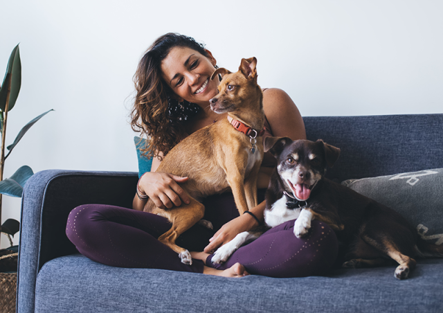 Woman sits on couch with two dogs
