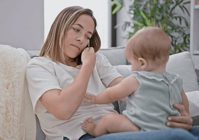 Mother on phone with baby on lap
