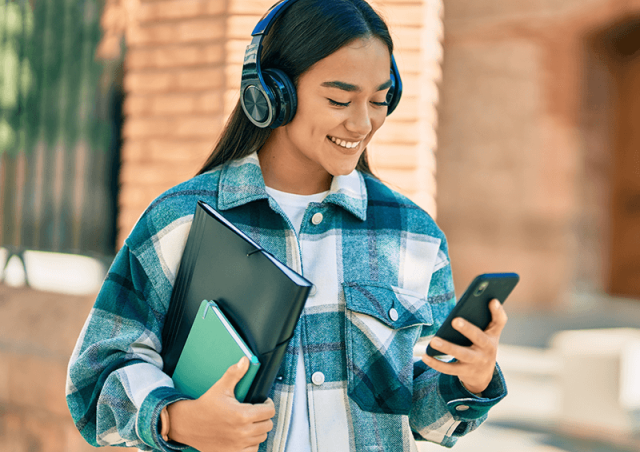 student with headphones looking at phone