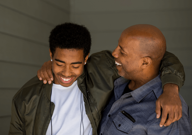 A dad puts his arm around his son