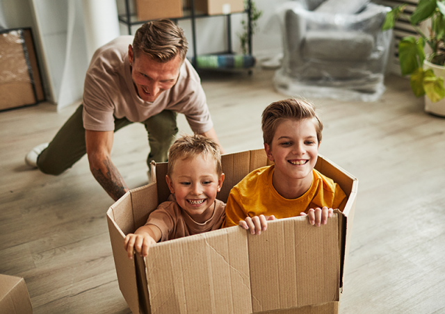 Father pushing two children in a box